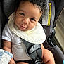 Oliver joined the competition — help win amazing prizes! baby, child, car_seat, curly_hair, white_bib, white_onesie, smile, infant, seatbelt, safety, cute, portrait, indoor, skin, hand, face, seat, clothing, expression, young