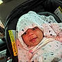 baby, car_seat, blanket, hood, smile, infant, child, patterned_cloth, wrapped, cute, indoors, seat, safety, adorable, car_interior, small_person, warm, happy, head_covering, portrait