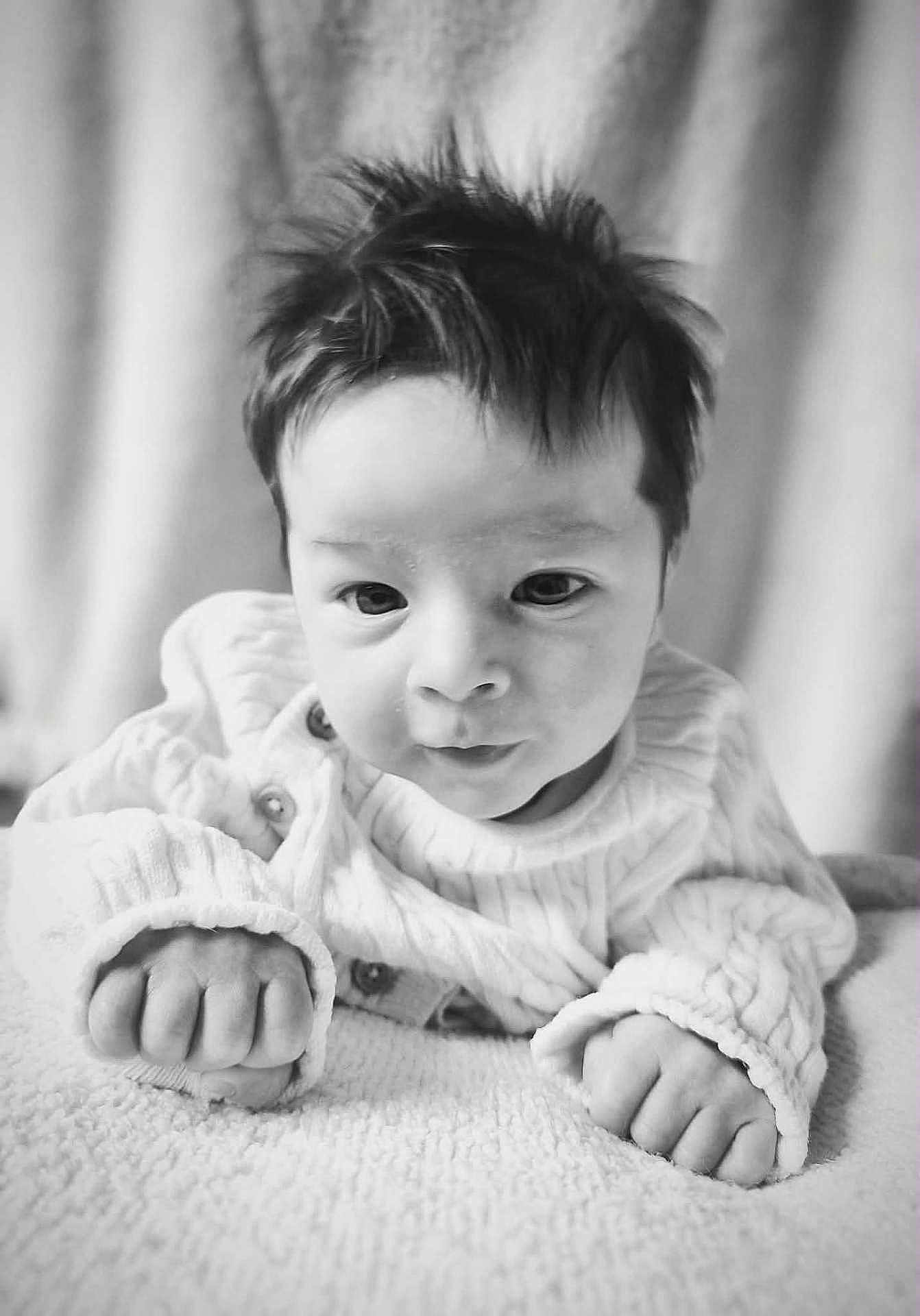 Nino participe au concours pour gagner de l'argent avec cette photo : baby, infant, black_and_white, closeup, face, hands, curly_hair, blanket, knitted_sweater, portrait, cute, soft_texture, lying_down, indoor, young_child, expression, skin, eyes, fingers, newborn