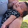 baby, sleeping, arm, person, clothing, outdoor, grass, hand, face, closeup, skin, infant, star_pattern, sleeveless, holding, peaceful, young_child, portrait, casual_wear, rest