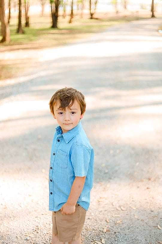 Maverick is registered to the contest to win money with this photo: child, facial_expression, flash_photography, fun, grass, hairstyle, happy, leisure, people_in_nature, person, plant, shorts, sleeve, smile, standing, street_fashion, summer, t_shirt, toddler, tree