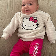 Willow is registered to the contest to win money with this photo: apparel, baby, child, clothing, cozy, cute, fabric, face, hello_kitty, indoor, infant, lying_down, person, pink_pants, portrait, quilt, smile, soft, sweater, young