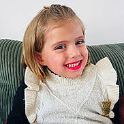 Lyla participe au concours pour gagner de l'argent avec cette photo : child, girl, smiling, lipstick, white_sweater, knitted, ruffles, brooch, green_couch, indoor, portrait, happy, young, casual_clothing, hairclip, seated, cozy, cute, fashion, face