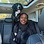 Pixel participe au concours pour gagner de l'argent avec cette photo : animal, backseat, black_dog, car_interior, casual_clothing, daytime, dog, happy, joy, outdoor_light, pet, portrait, scarf, seatbelt, smiling, sunroof, travel, trees, white_markings, woman