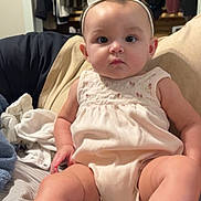 Lucymae joined the competition — help win amazing prizes! baby, child, infant, headband, clothing, bed, blanket, footwear, sitting, indoors, furniture, curious, cute, person, young_child, legs, face, expression, shoes, room