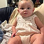 baby, child, infant, headband, clothing, bed, blanket, footwear, sitting, indoors, furniture, curious, cute, person, young_child, legs, face, expression, shoes, room