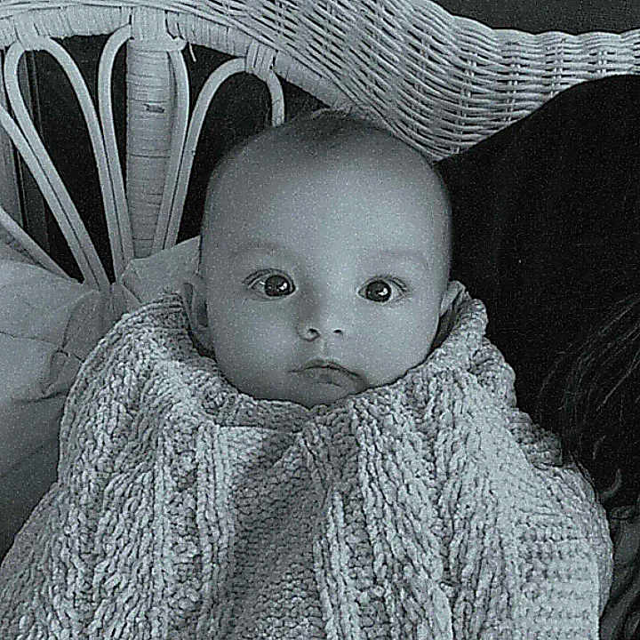Lucymae is registered to the contest to win money with this photo: baby, black_and_white, blanket, child, cozy, curious, cute, face, indoor, infant, knit, monochrome, person, portrait, seated, soft, texture, warm, wicker_chair, young