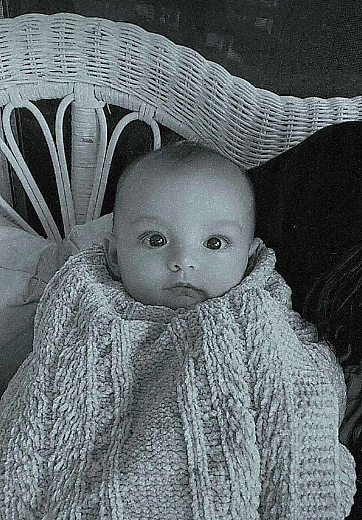 Lucymae is registered to the contest to win money with this photo: baby, infant, blanket, knit, wicker_chair, indoor, portrait, child, cute, face, curious, seated, cozy, monochrome, black_and_white, young, person, warm, texture, soft