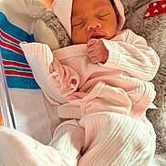 Goddess is registered to the contest to win money with this photo: newborn, baby, sleeping, pink_clothing, hat, blanket, plush_toy, cozy, indoors, infant, peaceful, cute, child, soft, resting, wrapped, small_hands, portrait, warm, cute_outfit
