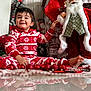 toddler, child, pajamas, red, white, christmas, holiday, decorations, santa_claus, doll, floor, reflection, smile, happy, indoors, festive, ornaments, toy, cozy, celebration