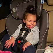 Janiyah is registered to the contest to win money with this photo: toddler, car_seat, child, seatbelt, tongue_out, playful, pink_shoe, clothing, car_interior, sitting, seat, baby, person, cute, hair_up, funny_expression, safety_harness, indoor, young_child, smiling