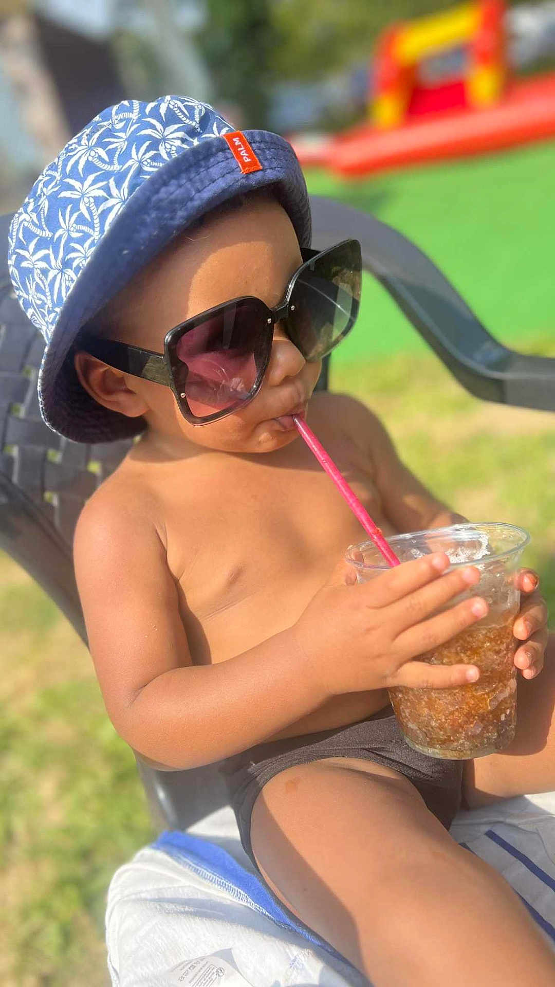 Kassym a rejoint le concours — aidez-le/la à gagner de superbes lots ! child, toddler, sunglasses, bucket_hat, hat, drink, plastic_cup, straw, chair, outdoor, sunny, summer, bare_torso, swimwear, legs, grass, backyard, vacation, relaxing, portrait