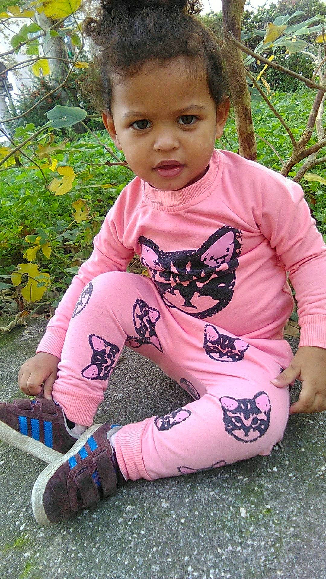 Shaïla S participe au concours pour gagner de l'argent avec cette photo : abdomen, arm, child, fun, girl, grass, infant, leg, pattern, person, pink, plant, play, sitting, skin, smile, toddler, tree, trunk