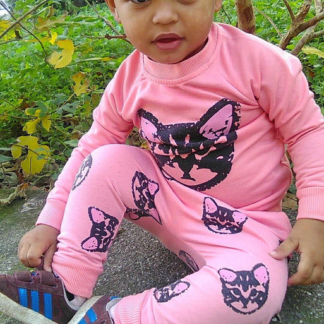 Shaïla S participe au concours pour gagner de l'argent avec cette photo : abdomen, arm, child, fun, girl, grass, infant, leg, pattern, person, pink, plant, play, sitting, skin, smile, toddler, tree, trunk