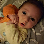 Arthur a rejoint le concours — aidez-le/la à gagner de superbes lots ! baby, infant, face, hand, yellow_clothing, orange_sleeve, bed, bedding, gray_pattern, curious_expression, wide_eyes, lying_down, close_up, soft_texture, child, newborn, cute, indoors, portrait, person