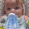baby, bottle, blanket, curly_hair, cushion, face, feeding, infant, inside, lying_down, person, portrait, resting, soft_texture, toddler, water_bottle, young_child, blue, white, patterned_background