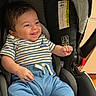 baby, child, infant, smiling, happy, portrait, car_seat, sitting, striped_shirt, blue_pants, clothing, indoor, vehicle, safety_harness, sunlight, brown_hair, face, eyes, hand, playful