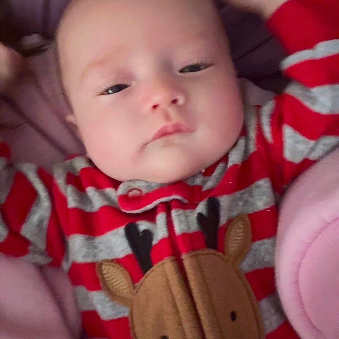 Sky is registered to the contest to win money with this photo: baby, bed, blanket, child, clothing, cute, face, gray_stripes, head, indoors, infant, onesie, plush, portrait, red_stripes, reindeer, resting, sleepy, soft_texture, young