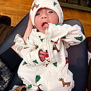 Sky joined the competition — help win amazing prizes! baby, infant, pajamas, hat, reindeer, christmas_tree, hand, face, eyes, mouth, clothing, newborn, person, indoor, floor, legs, sitting, cozy, cute, holiday