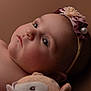 baby, infant, headband, flower, pearl, soft_toy, closeup, portrait, skin, face, blue_eyes, cheeks, nose, ear, child, laying_down, warm_tones, background, cute, expression