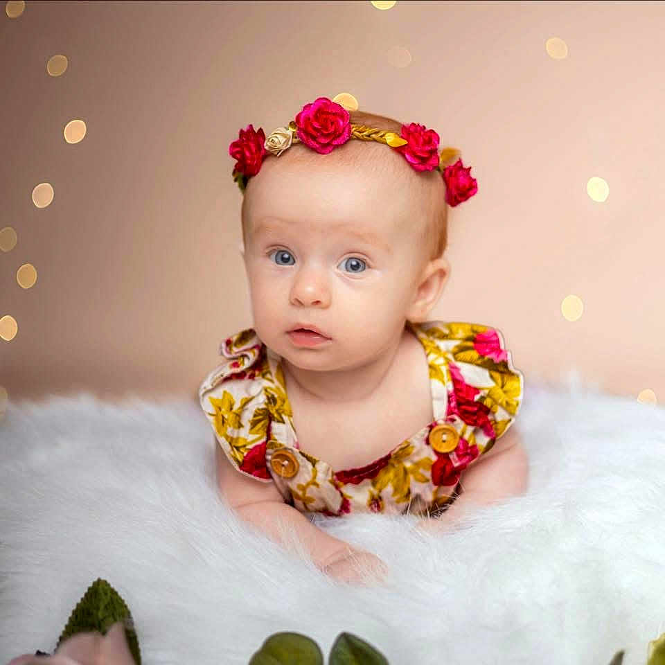Taylor joined the competition — help win amazing prizes! baby, infant, flower_headband, dress, blue_eyes, fluffy_surface, portrait, cute, child, soft_lighting, indoor, bokeh, skin, face, head, person, newborn, adorable, colorful, young