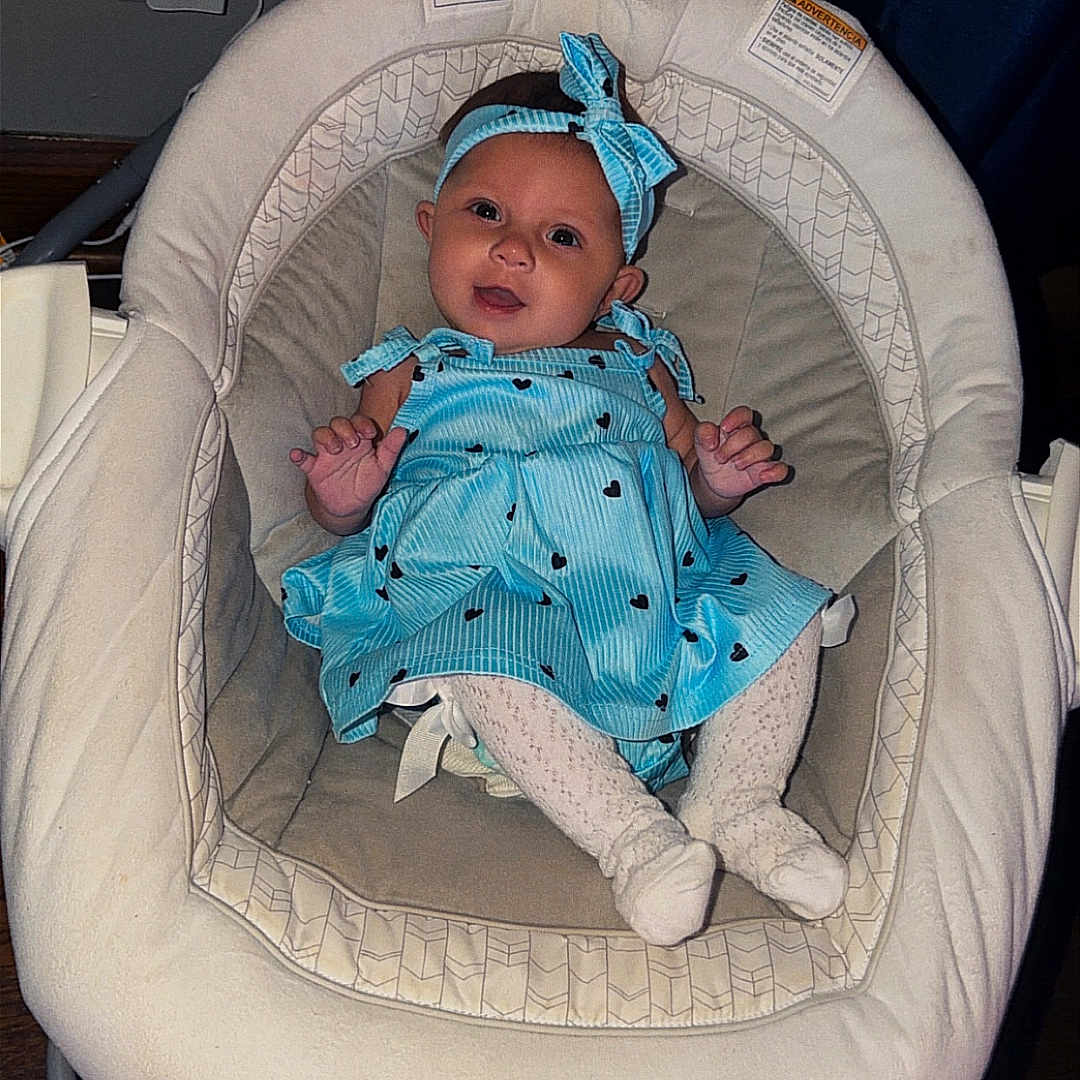 Kendall joined the competition — help win amazing prizes! baby, infant, blue_dress, headband, baby_rocker, soothing_vibration, happy, indoor, cushion, wooden_floor, clothing, person, smiling, cute, child, small_hands, white_socks, seat, comfort, relaxed