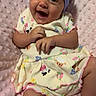 baby, infant, smiling, headband, purple_bow, blanket, pink, cute, clothing, patterned, face, happy, lying_down, child, skin, small_hands, legs, soft_texture, indoors, portrait