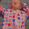 baby, infant, child, portrait, lying_down, onesie, pink_clothing, strawberries, rainbows, hearts, flowers, cherries, colorful, bed, blanket, indoor, face, eyes, serious_expression, photography