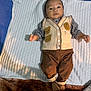 baby, infant, child, face, vest, clothing, pants, blanket, bottle, footwear, barefoot, lying_down, indoor, cute, expression, person, soft_texture, brown, beige, comfort