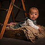 baby, infant, wooden_ladder, burlap_cloth, wooden_drawer, curious, wide_eyes, studio, dim_lighting, rustic, brown, cozy_clothing, child, portrait, cute, indoors, floor, expression, small_hands, surprised