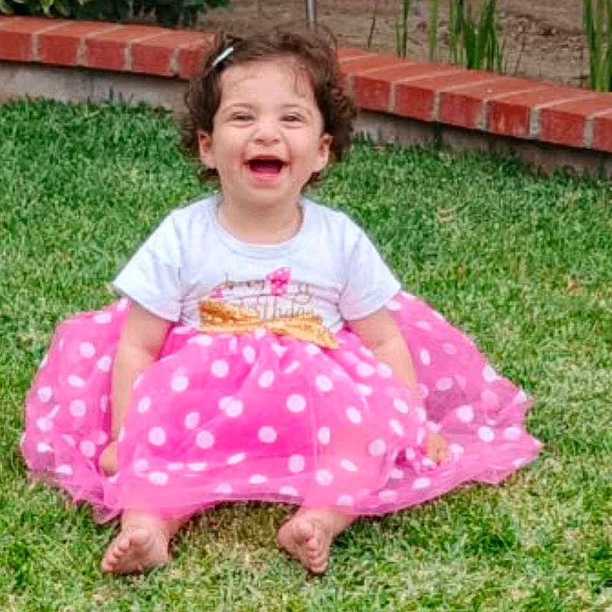 Victoria Grace joined the competition — help win amazing prizes! toddler, child, smiling, grass, pink_skirt, polka_dot, outdoor, happy, sitting, greenery, garden, brick_wall, window, curly_hair, barefoot, white_shirt, daylight, cute, playful, joyful