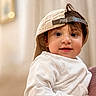 toddler, child, face, eyes, smile, cap, hat, clothing, white_shirt, portrait, indoors, person, cute, baby, young_child, headwear, hair, skin, expression, holding