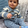 Ezel is registered to the contest to win money with this photo: toddler, child, sitting, couch, pillows, sweater, striped_clothing, pants, socks, blue, white, cozy, indoor, smiling, face, hand, furniture, home, cute, portrait