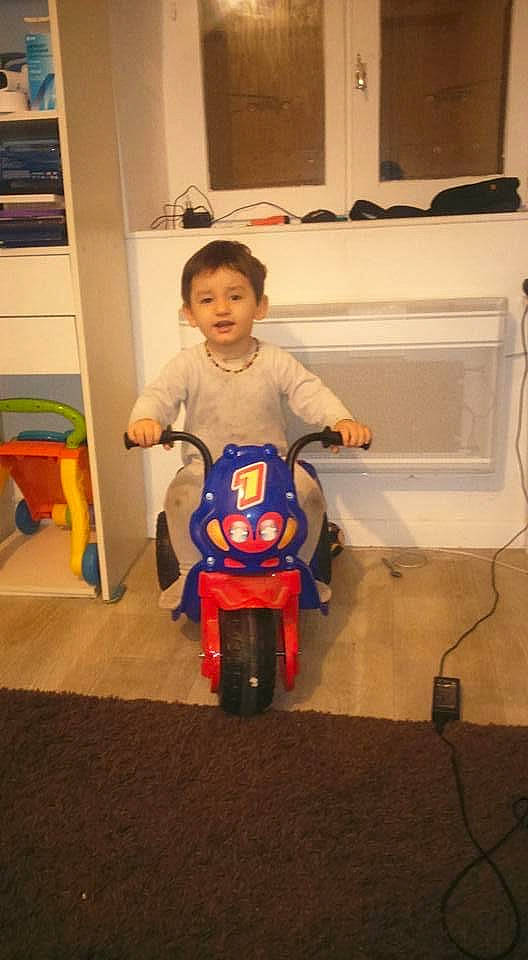 Jordan participe au concours pour gagner de l'argent avec cette photo : automotive_design, automotive_tire, baby, baby_toddler_clothing, child, floor, flooring, happy, human_body, person, product, riding_toy, shelf, sitting, standing, t_shirt, tire, toddler, toy, vehicle
