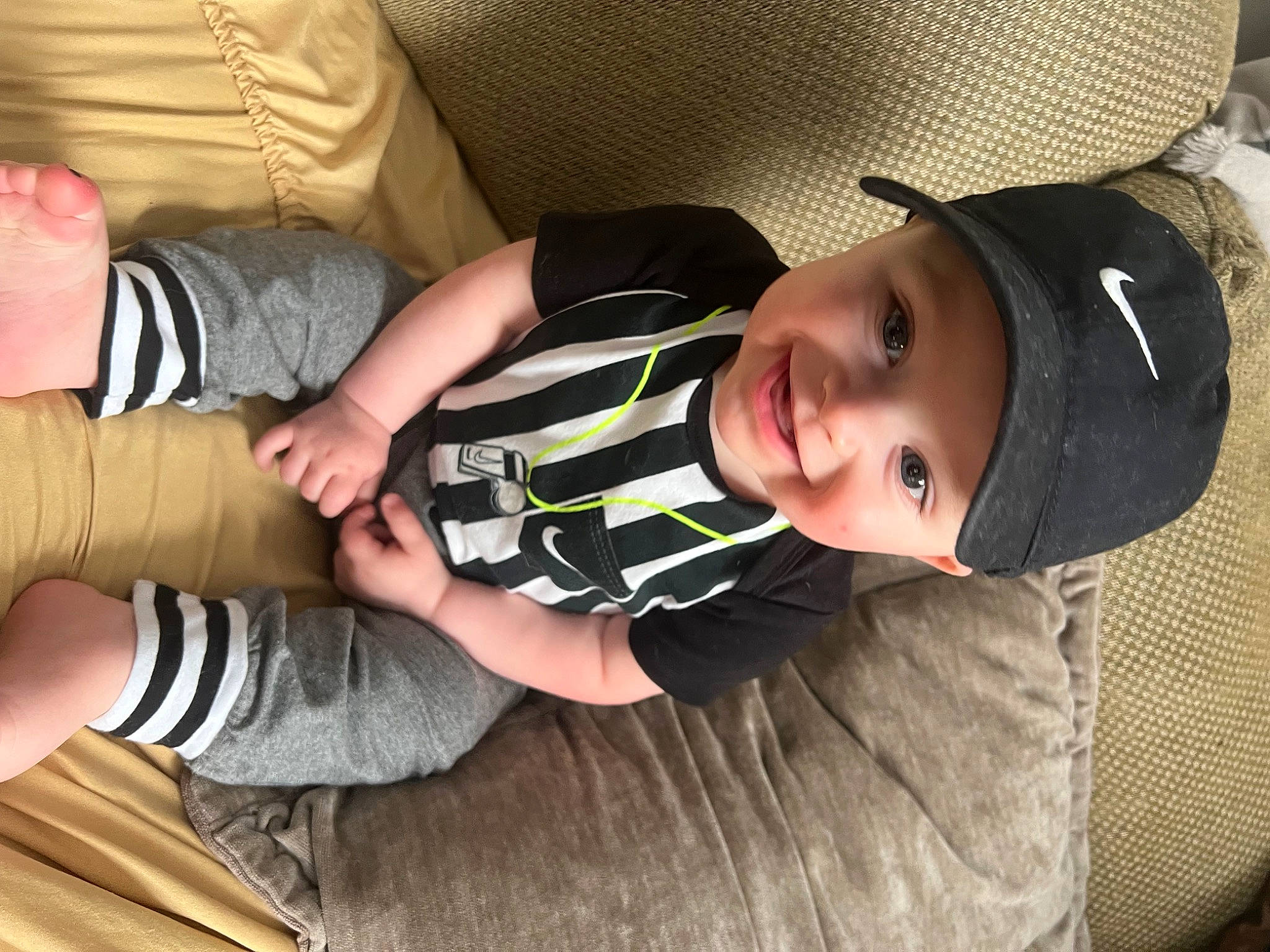 Chase is registered to the contest to win money with this photo: baby, baby_toddler_clothing, child, comfort, elbow, finger, gesture, grass, hand, hat, headwear, joy, knee, person, sitting, skin, sleeve, smile, sock, sun_hat