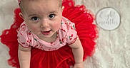 Amaya is registered to the contest to win money with this photo: baby, child, tutu, headband, pink, red, cherry_pattern, cute, portrait, soft_blanket, white, infant, smiling, looking_up, sitting, clothing, adorable, indoor, person, baby_fashion