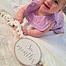 Amaya is registered to the contest to win money with this photo: baby, infant, smiling, headband, flower, purple_dress, blanket, soft_texture, indoor, floor, six_months_sign, cute, child, person, happy, lying_down, portrait, candid, decor, young_child