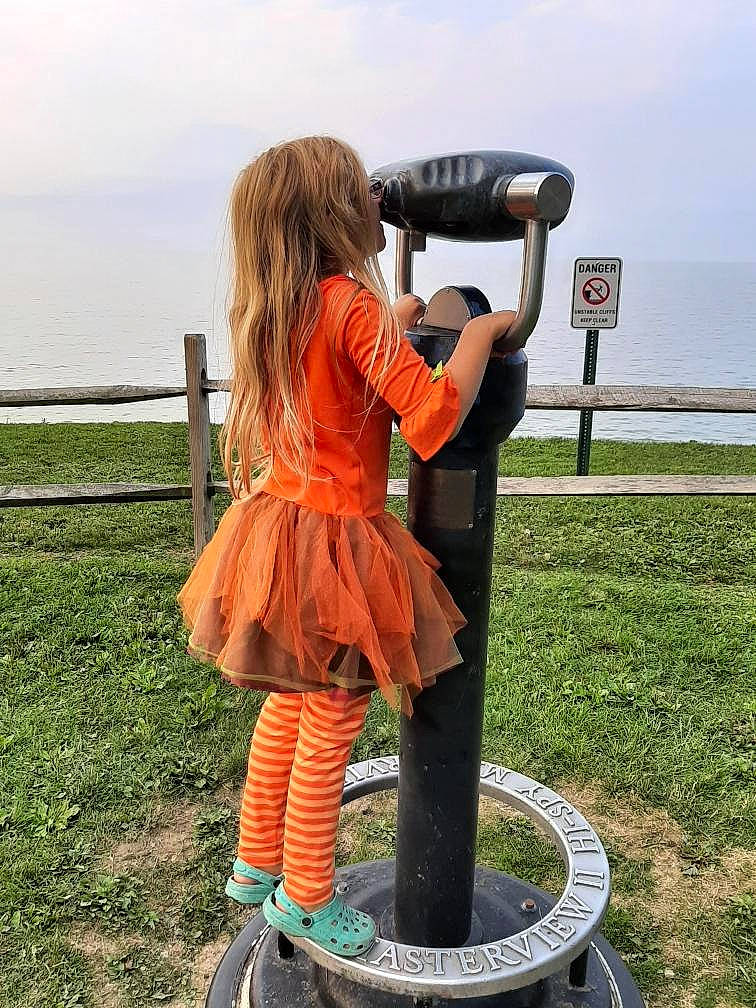 Regan is registered to the contest to win money with this photo: art, boot, cloud, costume, fence, fun, gas, grass, human_leg, knee, leisure, optical_instrument, people_in_nature, person, personal_protective_equipment, recreation, sky, thigh, vacation, waist