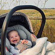 Ella participe au concours pour gagner de l'argent avec cette photo : baby, car_seat, blanket, smiling, outdoor, wildflowers, fence, grass, happy, infant, nature, child, seatbelt, cozy, cute, portrait, sunlight, peaceful, field, young
