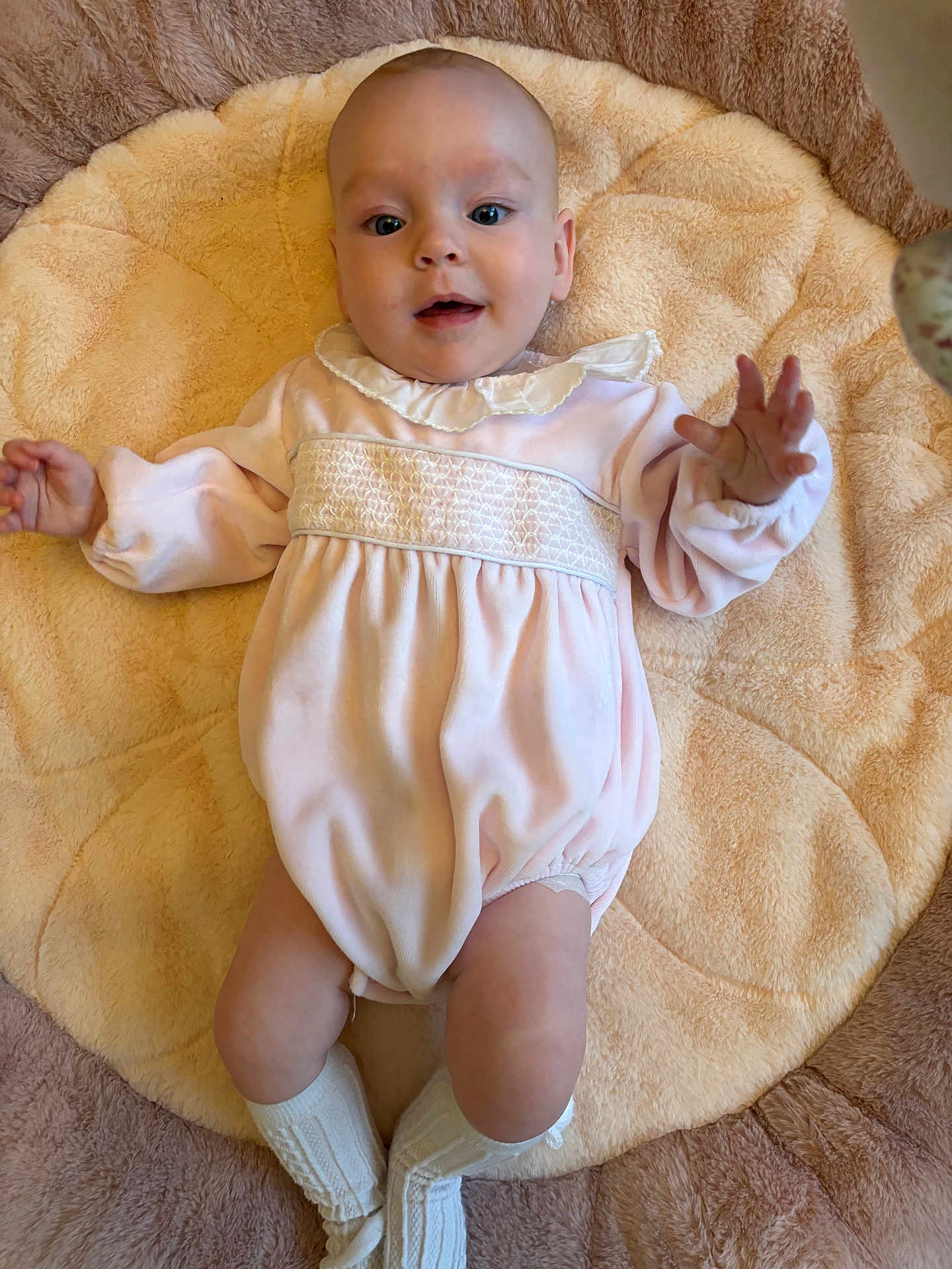 Annie is registered to the contest to win money with this photo: baby, infant, child, pink_outfit, knitted_socks, plush_mat, soft_texture, lying_down, cute, portrait, indoor, comfortable, happy, baby_clothing, smiling, human, skin, face, hands, legs