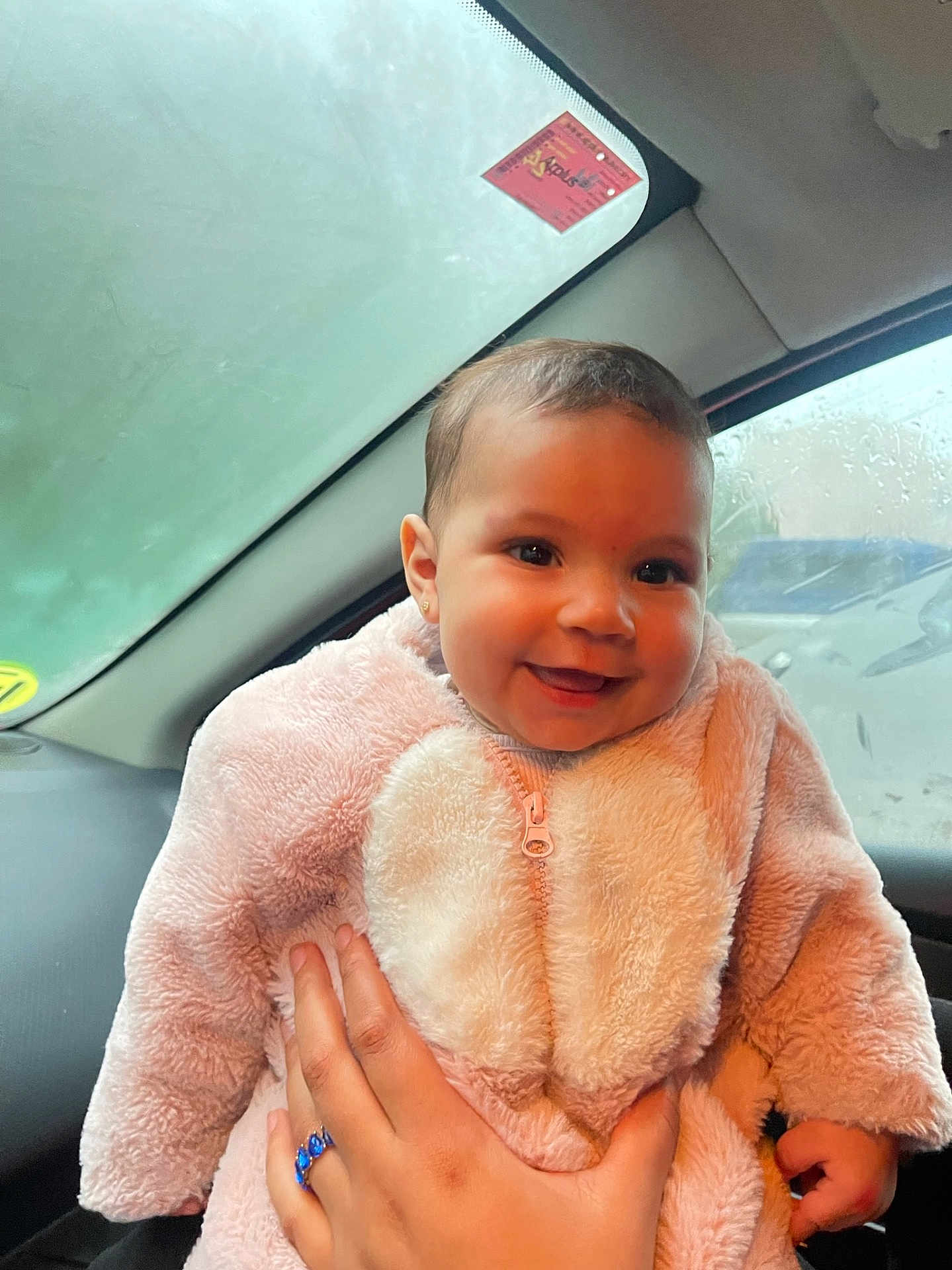 Sophia participe au concours pour gagner de l'argent avec cette photo : baby, child, smile, pink_jacket, hand, car_interior, window, rain, raindrops, face, person, cute, warm_clothing, earrings, portrait, happy, infant, young_child, human, holding