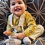 toddler, child, smiling, yellow_shirt, overalls, socks, winnie_the_pooh, couch, patterned_cushion, happy, indoor, person, seated, cute, young_child, playful, small_object, corduroy, casual_clothing, home