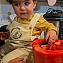 Zayne is registered to the contest to win money with this photo: toddler, child, face, overalls, winnie_the_pooh, fruit, watermelon, strawberries, berries, kitchen, countertop, hand, curly_hair, yellow_clothing, plate, container, cabinet, appliance, cute, indoor