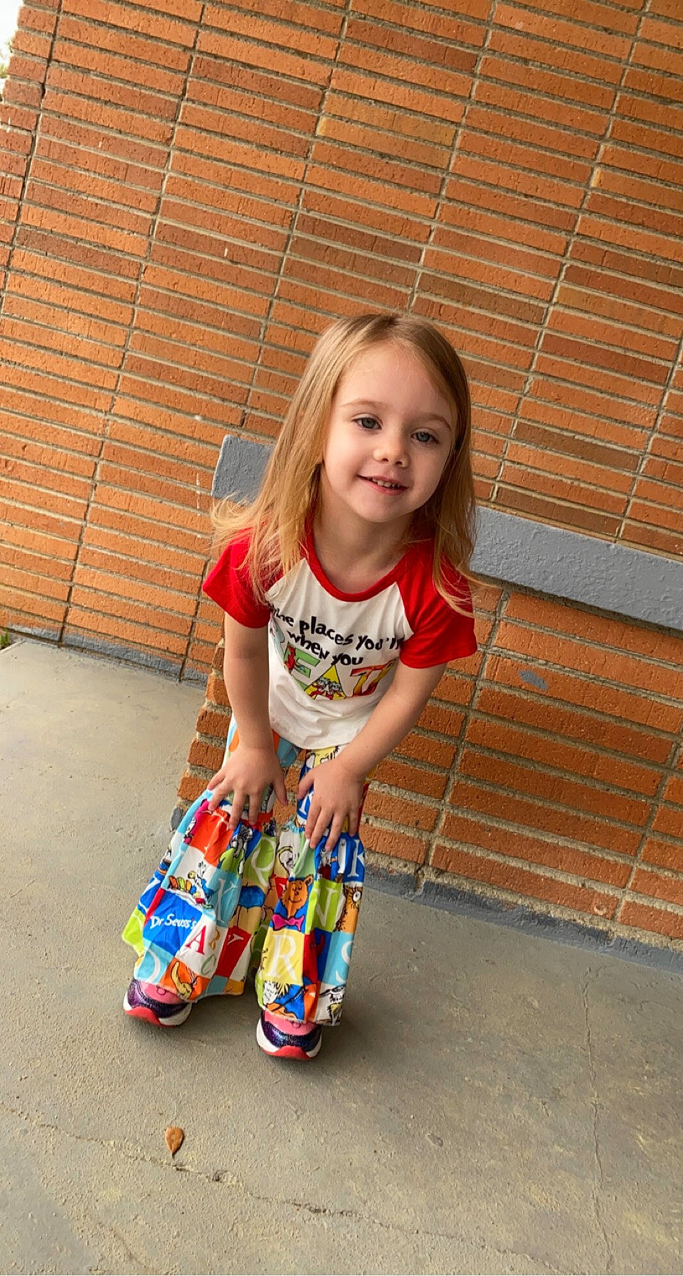 Amelia is registered to the contest to win money with this photo: baby_toddler_clothing, brick, child, electric_blue, foot, fun, happy, human_leg, joy, knee, orange, pattern, person, play, sandal, sitting, sleeve, smile, t_shirt, thigh
