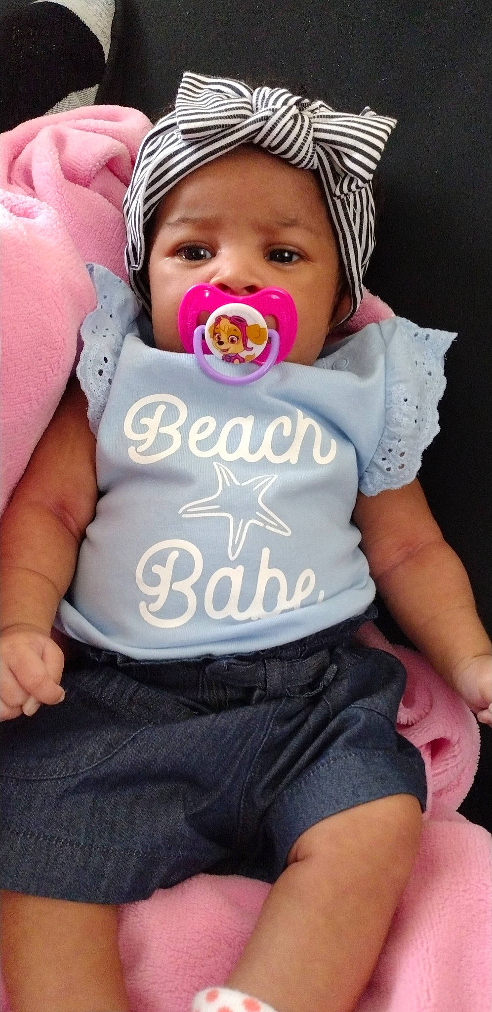 Riah is registered to the contest to win money with this photo: arm, baby, baby_toddler_clothing, cheek, cool, face, finger, gesture, hand, happy, headgear, headwear, human, mouth, organ, outerwear, person, pink, shorts, skin