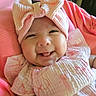 baby, smiling, pink_bow, headband, cute, infant, tongue_out, pink_clothing, blanket, happy, closeup, portrait, child, soft_texture, indoors, cozy, adorable, baby_girl, cheerful, sleepwear