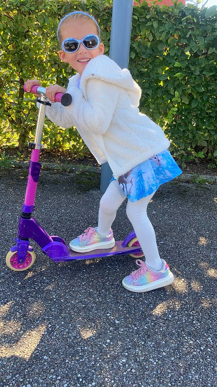 Lina participe au concours pour gagner de l'argent avec cette photo : electric_blue, eyewear, footwear, fun, goggles, grass, happy, joy, kick_scooter, magenta, person, pink, plant, recreation, riding_toy, sneakers, sunglasses, tire, toddler, tree