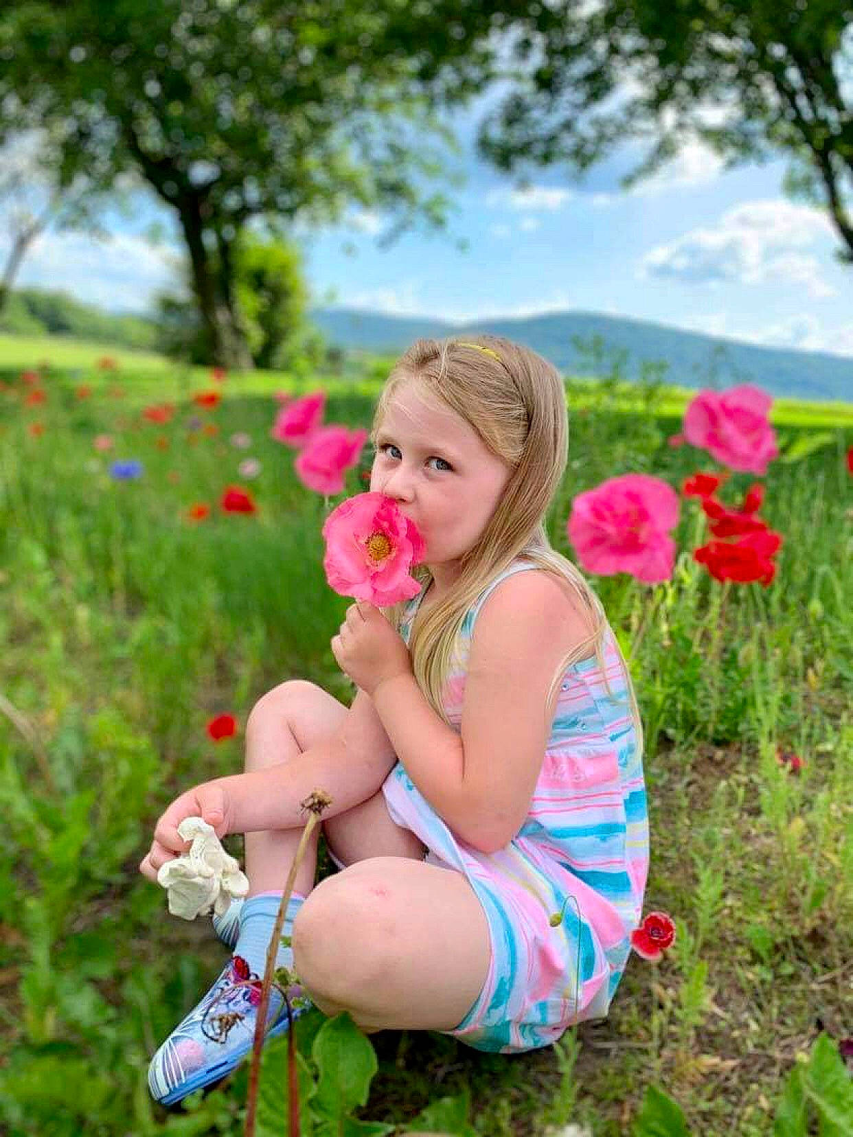 Peightyn is registered to the contest to win money with this photo: automotive_wheel_system, child, finger, flower, footwear, grass, grassland, happy, meadow, people_in_nature, person, photo_shoot, photography, pink, plant, sitting, smile, spring, summer, wheel
