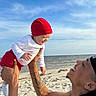 Zamir is registered to the contest to win money with this photo: baby, man, beach, ocean, sky, sand, smile, happy, hat, red_clothing, white_clothing, tattoo, earring, playing, outdoor, summer, portrait, joy, family, fun