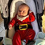 baby, infant, stroller, red_clothing, santa_outfit, blanket, indoor, face, person, cute, holiday, festive, carrying_device, footwear, expression, head, soft_toy, child, newborn, comfort
